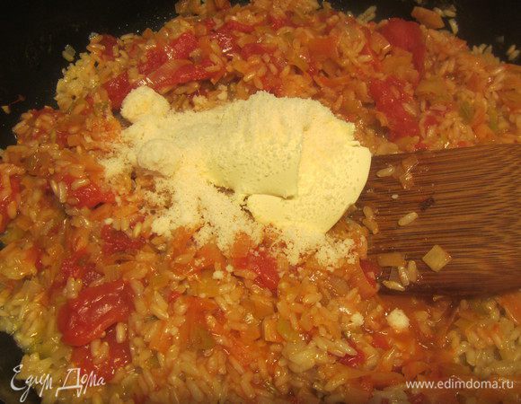 Добавляем луково-помидорную смесь в рис. Также добавляем сливочное масло и тертый пармезан. Все перемешиваем.
