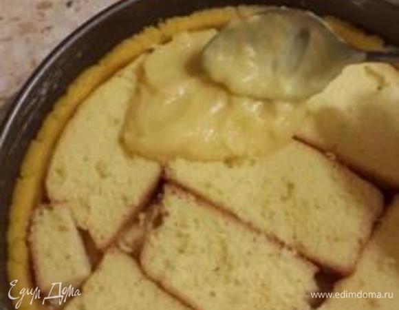 Достаём наше песочное тесто их холодильника. Распределяем его по форме (у меня 22см)пальчиками и делаем хорошие края (начинки у нас достаточно). Затем выкладываем половину заварного крема. На крем выкладываем кусочки бисквита и сверху оставшийся крем.