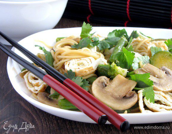 Добавить крупно рубленную зелень кинзы, ломтики омлета и подавать.