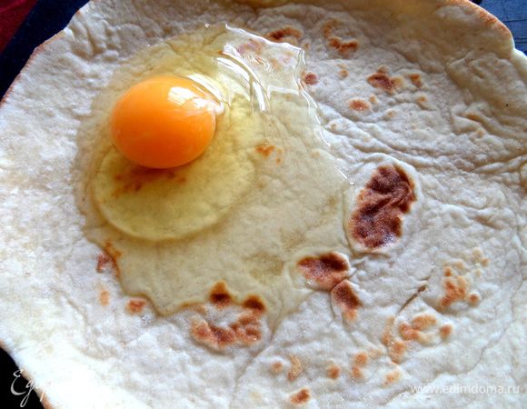 Вбиваем в центр (диаметр 20 см) яйцо и размазываем его (вилкой или силиконовой лопаточкой) по всей поверхности лавашика.