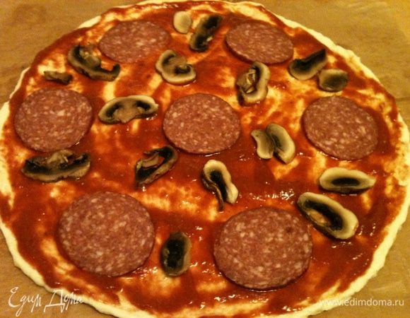 Уложить на соус все тонко нарезанные продукты - колбасу, грибы .