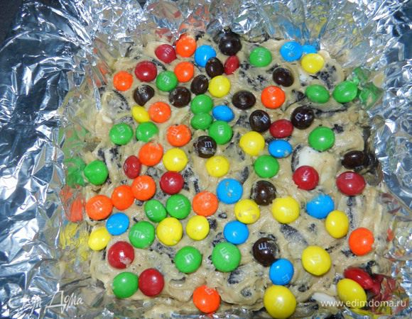Нанести полученную смесь на подготовленную смазанную форму для выпечки. Сверху посыпать 1/2 ст. молочных конфет M&M's.