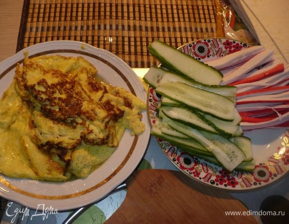 Порезать крабовые палочки соломкой, огурцы тонкими дольками, сделать омлет из яиц и немного молока.