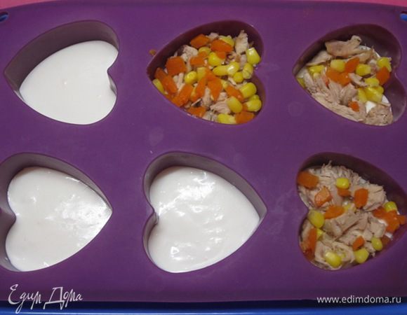 Достать из холодильника формочки и выложить кусочки куриного мяса, кукурузу и кубики моркови.