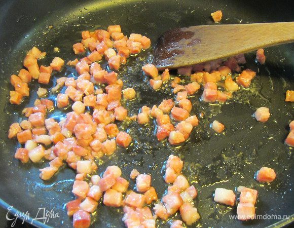 Разогреваем в сотейнике оливковое масло и обжариваем на нем порезанный кубиками бекон до золотистого цвета.
