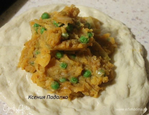 Оставшееся тесто делим ровно пополам. Одну половинку также разминаем руками и выкладываем начинку.