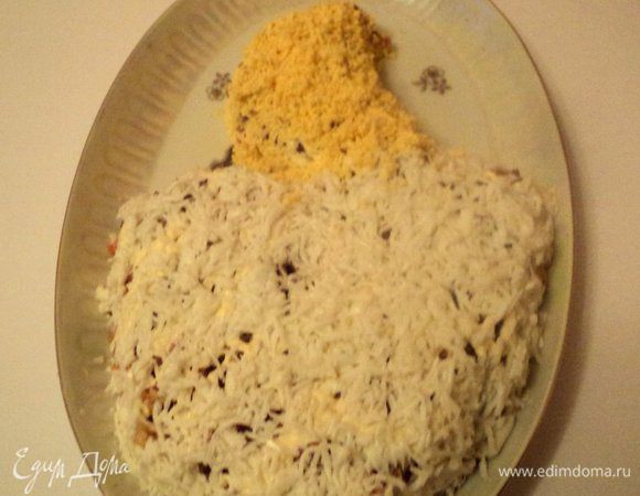 Яйца сварить вкрутую, почистить и разделить на белки и желтки, натереть на терке. Белками накрыть часть салата в виде хвоста птицы. Желтком посыпать туловище птицы.