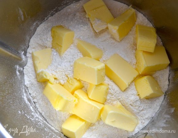 Добавить охлажденное сливочное масло кусочками и перетереть всё руками в крошку или измельчить в миксере в течение нескольких секунд.