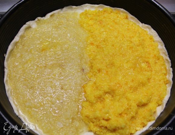 Половину теста распределяем по всей поверхности формы, сделав небольшие бортики. Визуально делим форму на две половины. На первую выкладываем измельченный лимон, на вторую - апельсин.