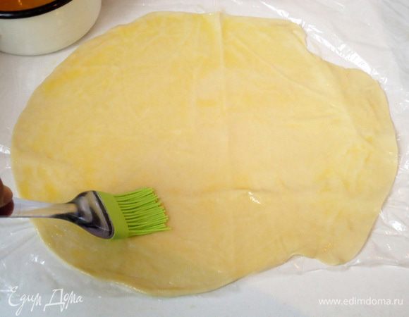 Каждый шарик скалкой раскатать в тонкую лепешку и смазать сливочным маслом.
