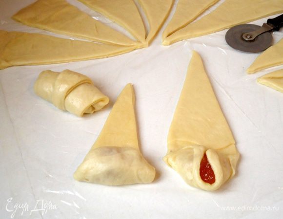 Разрезать её на сегменты - треугольники, 15-16 штук.
На широкий край треугольников положить по чайной ложке начинки (она может быть любой, по вашему вкусу). Закрепить бока так, что бы начинка не вытекла при выпечки в духовке. И свернуть рулетом. 
