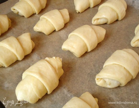 Выложить булочки на противень , застеленный пекарской бумагой, смазать их желтком с 1 ст.л. молока и присыпать сахаром.  Дать им время на расстойку, около 15 минут.
