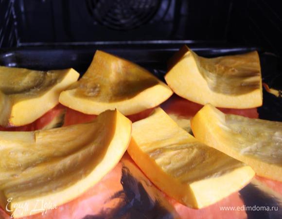 Поставить духовку разогреваться до 200 градусов.
Тыкву вымыть, очистить от мякоти и нарезать довольно крупными кусками вместе с кожурой. Уложить на застеленный противень и отправить в духовку минут на 20, может немного больше. 
Мякоть должна стать мягкой, но в то же время сохранить упругость.
