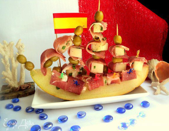 Хамон нарезать тонкими полосками. Обернуть кусочек дыни пластинкой хамона  и закрепить шпажкой. Я оформила подачу закуски в виде парусника, дополнительно украсив блюдо оливками. Приятного аппетита!