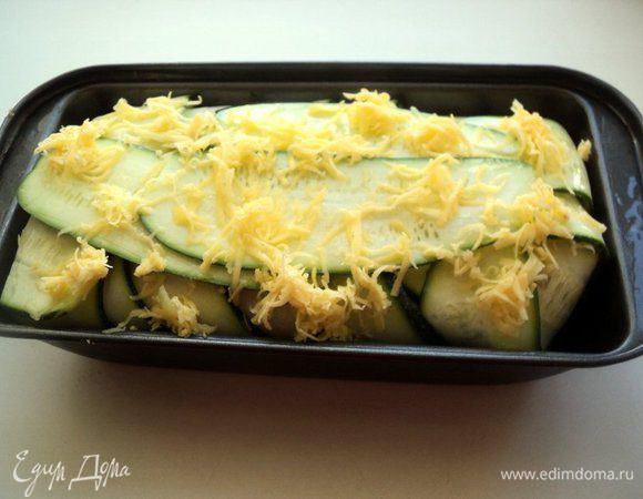 Выложить в форму фарш, хорошо уплотнить ложкой. Накрыть фарш свисающими пластинками кабачка. Смазать сверху растительным маслом и слегка присыпать тертым сыром.