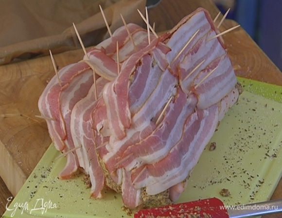Полоски бекона выложить на мясо, так чтобы горчичный слой был полностью закрыт, и закрепить бекон зубочистками.