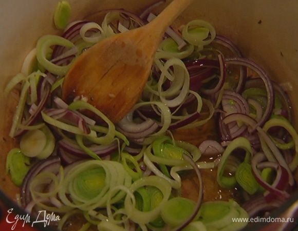 Разогреть в кастрюле с тяжелым дном сливочное и оливковое масло, всыпать тмин, помешивая, прогреть немного, затем выложить в кастрюлю весь лук и потомить его.