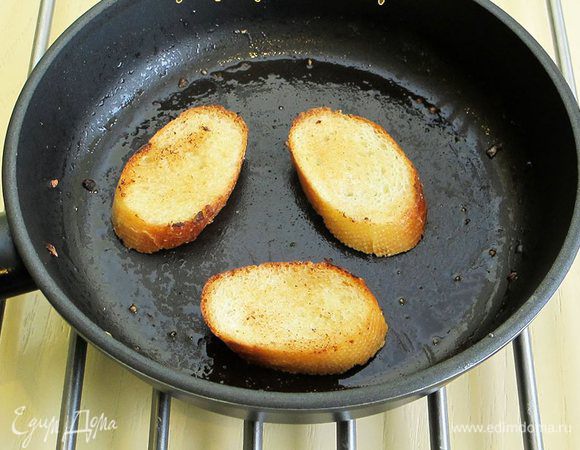 Теперь займемся приготовлением гренок. Багет нарезаем на небольшие ломтики. На сливочном масле обжариваем гренки с двух сторон. Натираем чесноком с солью и посыпаем свежемолотым перцем.