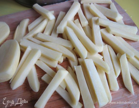  Вынуть  из воды,  нарезать каждую картофелину вдоль на две одинаковые половинки, положить на доску срезом вниз, сделать еще срез параллельно нижнему, потом  порезать брусочками вдоль толщиной 1 см. Важно, чтобы брусочки были примерно одинакового размера. Положить в холодную воду минут на 40.  Это делается для того, чтобы избавить картофель от излишнего крахмала. Откинуть на дуршлаг, дать стечь воде, затем обсушить  полотенцем. 