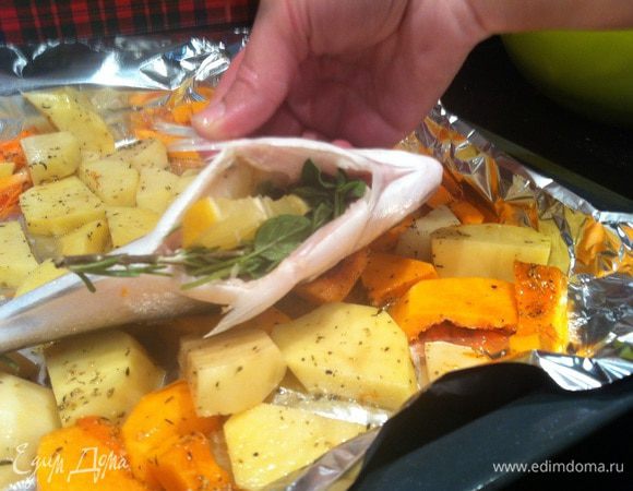 Овощи выложите на застеленный фольгой противень. Сверху выложите рыбу. В брюшко каждой рыбки положите по одной веточки орегано, розмарина и мяты, и вложите по 2-3 ломтика лимона.