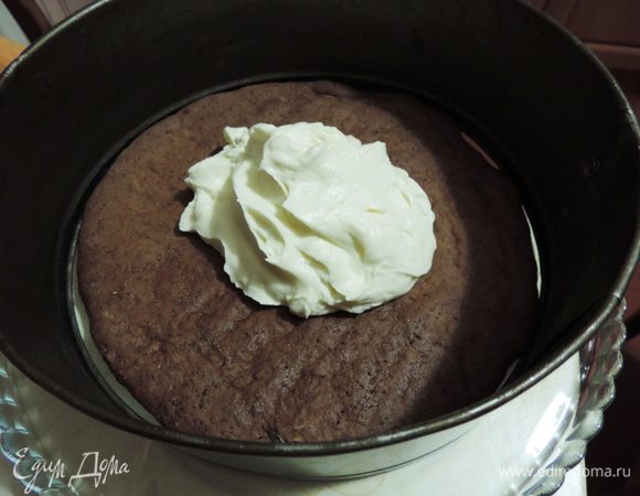 Торт собирать лучше в кондитерском кольце или использовать бортик от разъемной формы. Так он у вас обязательно получится ровным и красивым. Но раньше я прекрасно обходилась и без этих приспособлений. На блюдо кладем шоколадный корж. Заключаем его в кольцо. Выкладываем сверху примерно 1/5 часть крема. 