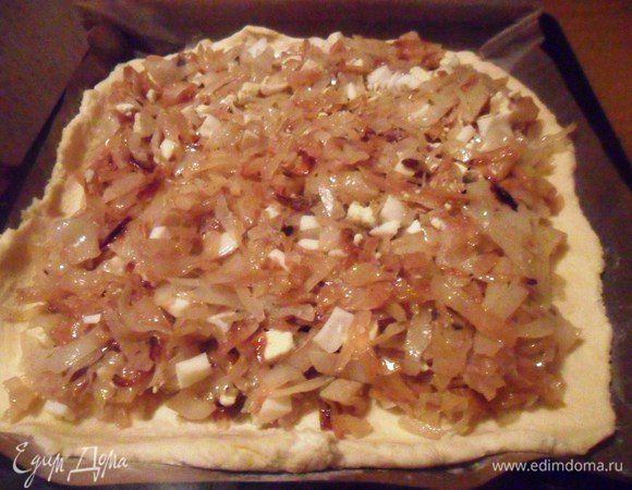 Охлаждённое тесто разделить на две части. Одну часть раскатать в прямоугольник по размеру противня. Перенести на противень. Выложить начинку не доходя до краёв 1,5 см.