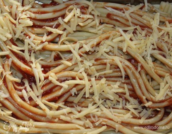 Смазать форму маслом. 
На дно уложить слой макарон, смазать его томатной пастой и слегка присыпать сыром. Если макароны мелкие, то удобнее их будет вначале смешать с пастой, затем уложить в форму и присыпать сыром.