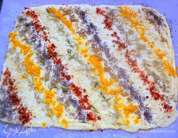 Раскатать тесто в пласт толщиной 0.5 см и смазать взбитым яйцом. Посыпать любимыми специями и семенами, чередуя их. Состав специй и семян можно варьировать по своему вкусу. Оставить для подъема теста на 20-30 минут.