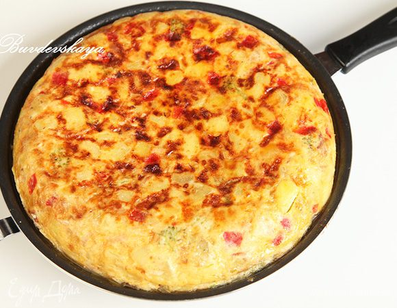 Накрываем второй сковородой и аккуратно, но энергично переворачиваем. При необходимости сливаем избытки масла и готовим на медленном огне минут 15. Берем большое плоское блюдо и выкладываем на него нашу тортилью! И чем менее у вас румяная получилась тортилья, тем лучше. Потому как она не должна иметь хрустящую корочку.