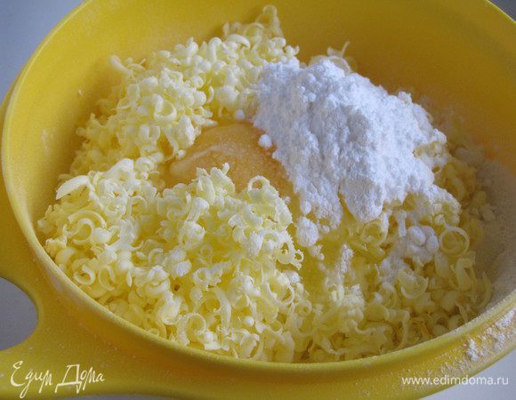 Для теста муку просеять в миску. Туда же натереть сливочное масло на крупной терке, добавить яйцо, сахарную пудру, соль.