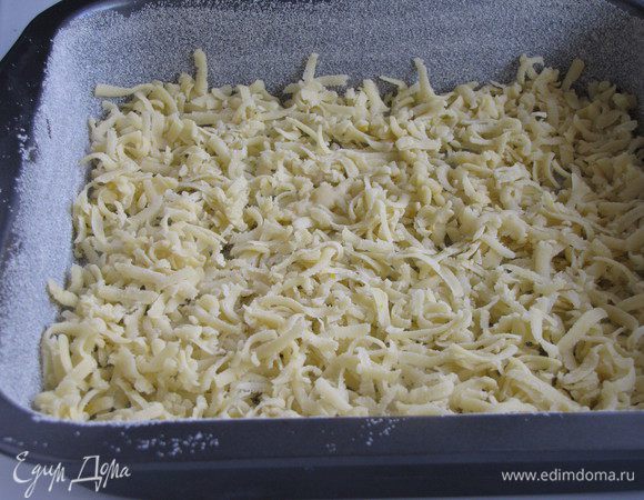 Квадратную жаропрочную форму со стороной 20-25 см. смазать сливочным маслом и присыпать манкой или мукой. Половину теста натереть на крупной терке и выстлать получившейся крошкой дно формы.