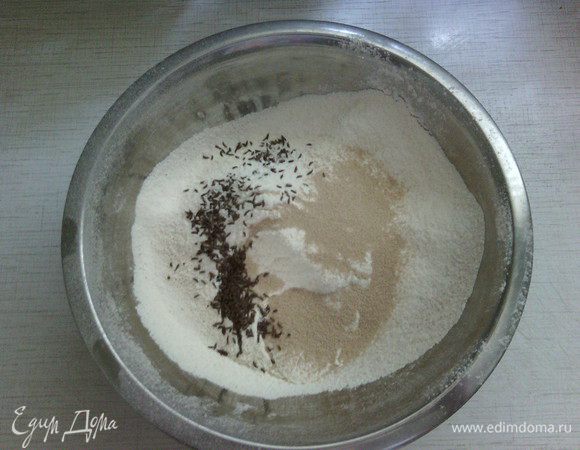В большую миску просейте оба вида муки, добавьте соль, дрожжи, тмин и перемешайте.