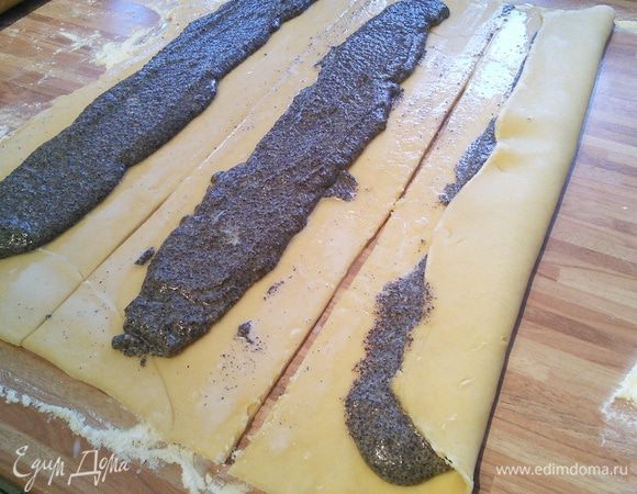 Маковую начинку распределить по середине каждой полоски. Смазать края теста молоком и свернуть в рулеты, немного прижать и перевернуть швом вниз. 