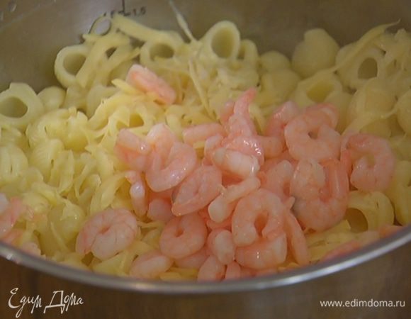 К горячим макаронам добавить половину натертого сыра, креветки (без рассола), влить сливки и все перемешать.