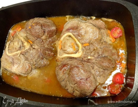 К мясу добавить пассерованные овощи, порезанный чеснок, и порезанные томаты. Посолить и поперчить. Закрыть крышкой и томить на медленном огне 2 часа, переворачивая каждые 20 минут. Если необходимо - то добавить воды.