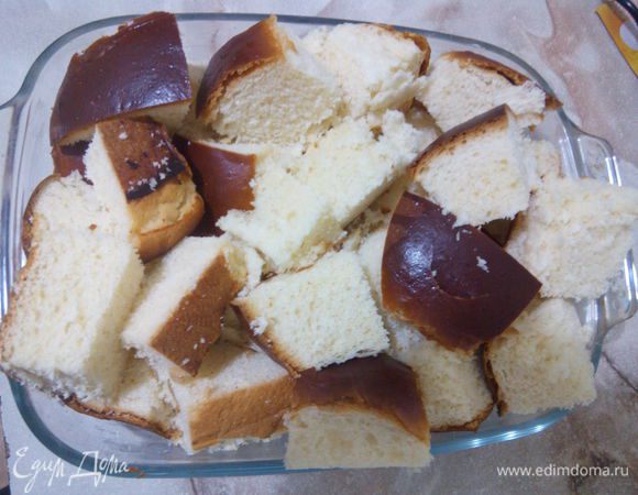 Для данного пудинга нам понадобится немного сладкий хлеб. У нас продаются большие булочки, они еле сладкие, я взяла таких 4 штуки и порезала на квадратики. Форму смазываем сливочным маслом и выкладываем хлеб.