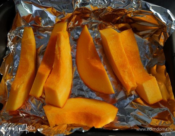 Форму для тарта (у меня диаметр дна 24, верх 28 см, высота 4 см) поставить охлаждаться в холодильник и достать маскарпоне. Включаем нагреваться духовку до 200 градусов. Ставим запекаться тыкву. Это очень просто. Не надо мучиться очищать её сырую от жесткой корки. Порезать тыкву на дольки. Очистить от семян и уложить в форму, застеленную фольгой, шкуркой вниз. Запекать в духовке 25-30 минут при 200 градусах до готовности.