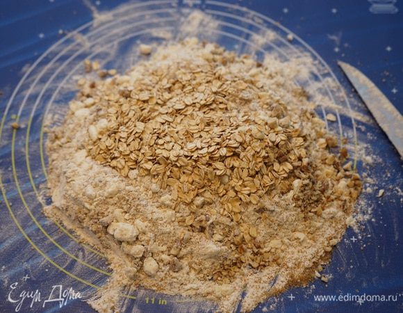 Добавить порубленные средним размером орехи и овсяные хлопья, затем добавить желток и месить еще минут 5, пока тесто не начнет сбиваться во влажные комки. Тестом как таковым масса не станет, а будет как бы влажной крошкой.