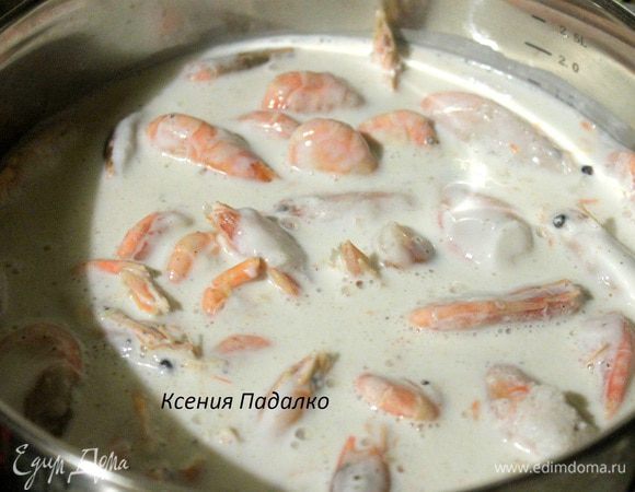 В кастрюлю к креветкам вылить сметану и оставшийся кефир. Все вместе хорошо перемешать. Включить огонь и довести до кипения на среднем огне.