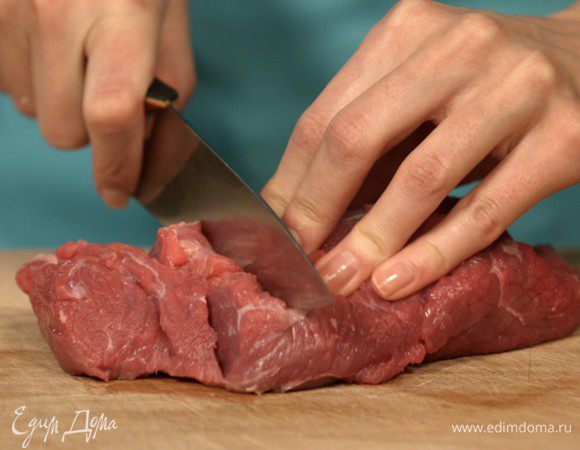 Нарезаем мясо поперек волокон, так наше блюдо получится нежным. Выкладываем нарезанную говядину в форму для запекания.