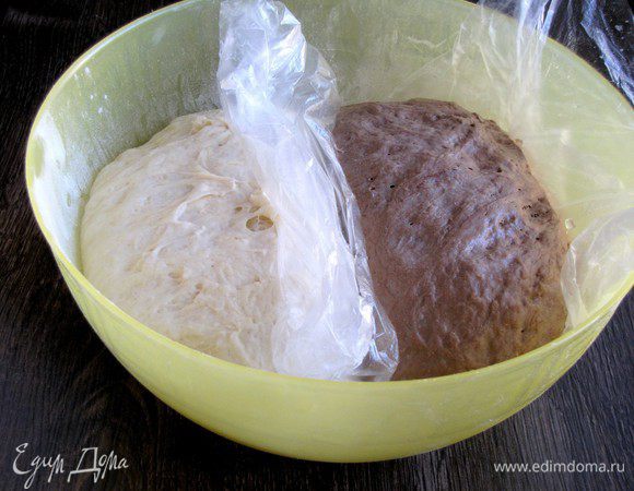 Оставшуюся муку разделить на две части и добавить к темной и светлой опаре. Замесить два вида теста. Муку стараемся не подсыпать. Если тесто липнет, то руки смазать маслом. Выложить тесто в миску, разделив пленкой. Оставить подниматься в теплом месте на 1 час, накрыв миску полотенцем. 