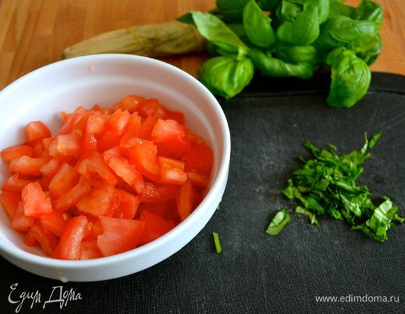 Помидоры залить кипятком и подержать в воде пару минут. Сделать крестовидные надрезы на каждом помидоре и снять шкурку. Помидоры разрезать, удалить семена и нарезать мелкими кубиками. Порубить базилик (или петрушку).