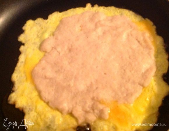 На разогретую сковороду с растительным маслом, мы выливаем яйца (не все), поджариваем слегка и потом выкладываем лепешку из фарша сверху, делала я это так: засунула одну руку в пакетик, как бы взяла лепешку на ладонь, второй рукой аккуратно отлепила прилипший к фаршу пакетик и с ладони опустила лепешку на яйца.