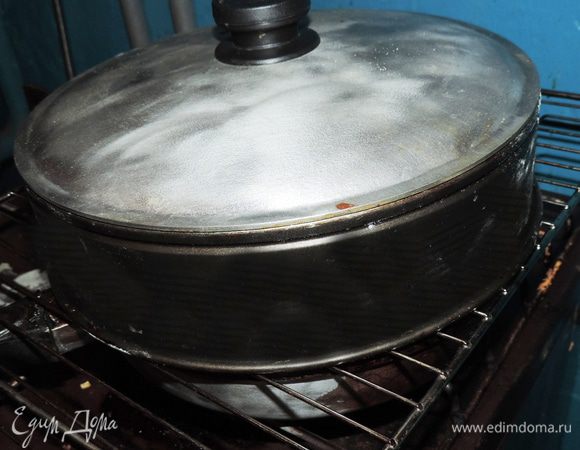 Выкладываем фольгу с рисом в чугунную сковороду. Дно сковороды обязательно выстелить слоем фольги, чтоб не пришлось потом ее отчищать.
Нам следует на большом огне накалить сковороду, чтоб из смеси начал выходить дым. 
Тогда сверху ставим решетку, можете достать ее из духовки, на решетку кладем скумбрию. Накрываем ее куполообразной крышкой, с диаметром равным диаметру сковороды. 
У меня такой крышки не оказалось. Мне пришлось поставить на решетку кольцо от разъемной формы, которое я накрыла крышкой от сковороды))) 
Вот так выглядит моя сложная конструкция. Прошу прощение за фото. Оно сделано вечером при плохом освещении в подсобном помещении)))
