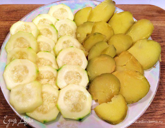 Цукини вымыть, порезать на кружочки толщиной 0,5 см, опустить на 5 минут в соленый кипяток, затем вынуть шумовкой и обсушить.

Картофель отварить в мундире, остудить и очистить. Порезать кружочками, как и цукини.

