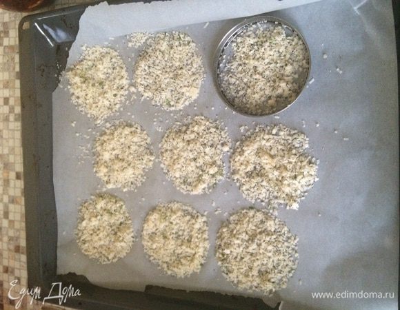 Разогреваем духовку до 200 градусов. На холодный противень стелим лист пекарской бумаги и через кулинарное кольцо насыпаем тонкие сплошные сырные круги.