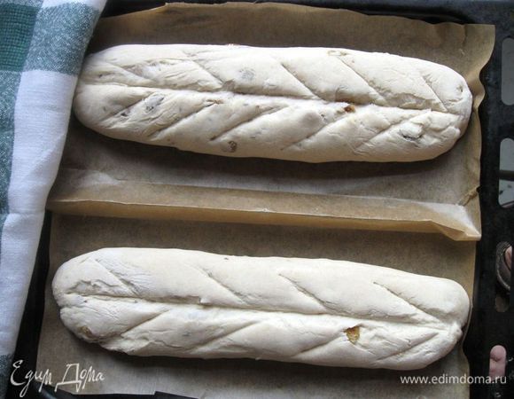 Духовку разогреть до 230 градусов, вниз поставить емкость с кипятком. На багетах сделать разрезы острым ножом (скальпелем, бритвой).  Один, более глубокий  – вдоль багетов, другие – по типу листа растения - косые, более мелкие. Разрезы, конечно, могут быть и другие.