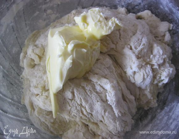 В два этапа добавить размягченное сливочное масло, каждый раз тщательно вмешивая его в тесто.