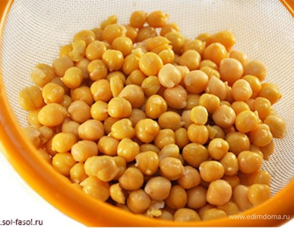 Я использую уже готовый нут в собственном соку (370 мл. - масса сухого нута 240 гр.). Если подобрать качественный продукт, как это сделала я, то никто не догадается, что этот нут сварили не Вы. Многие не хотят затевать процесс на два дня с предварительным вымачиванием нута, затем его многочасовой варкой. Именно для таких читателей мой рецепт. Обратите внимание, если в Вашем нуте уже есть в составе соль, то солить готовый хумус следует только в самом конце при необходимости.

Поместите нут в просторную глубокую миску и промойте под теплой проточной водой. При этом слегка перетирайте нут между ладонями (без сильного нажима), чтобы отошла белая внешняя оболочка.  

Некоторые считают эту процедуру необязательной («перемелется»  - никто не заметит). Но, поверьте, это влияет как на цвет, так и на вкус готового блюда. Операция совсем несложная, белую «шелуху» через 30-60 секунд работы ладонями можно легко собрать с поверхности воды. Именно для этого посуда должна быть глубокой: тяжелый нут будет покоиться на дне, а легкая шелуха будет уплывать в раковину в процессе «легкого перетирания» и перемешивания. В процессе такой очистки отойдет целая чаша белой шелухи.

Промытый нут без внешней оболочки откиньте на дуршлаг, чтобы стекла лишняя вода. Самая трудоемкая часть работы выполнена!
