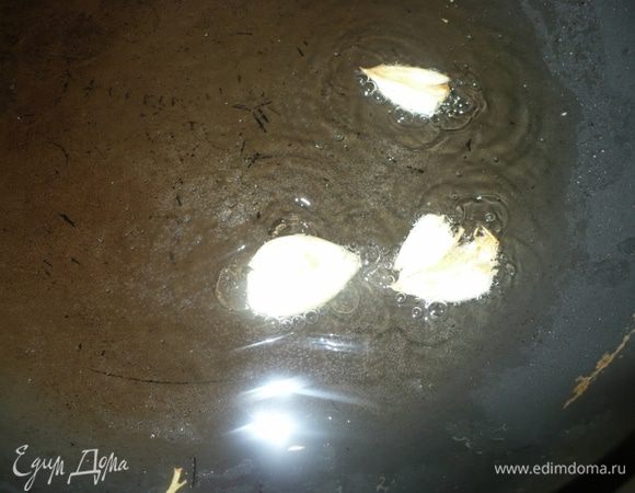 В разогретое масло кинуть раздавленные 2-3 дольки чеснока.